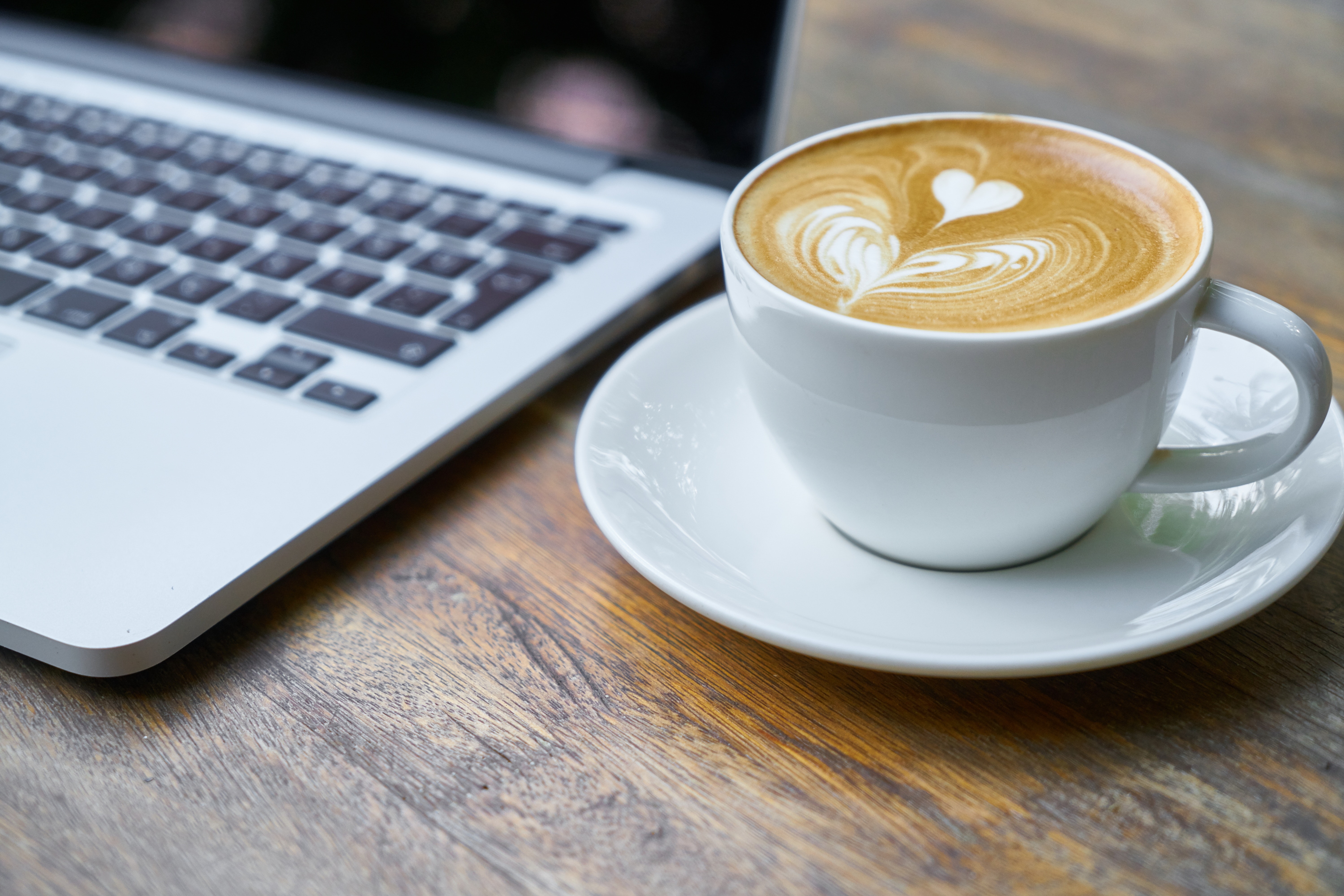 image of a caffe latte next to a laptop on a table